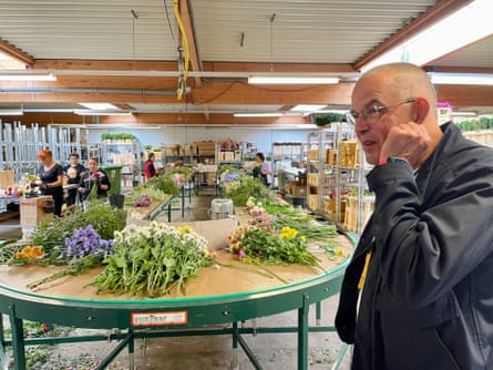 Christian Linden, founder and CEO of IBH Export, in his flower auction house, with workers assembling bunches of flowers in the background.