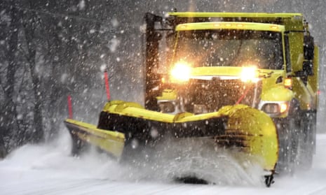 A yellow snow plow clears snow in a storm.