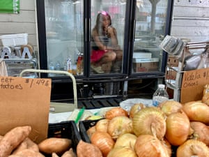 A woman sits inside a refrigerated cabinet at a farmers market