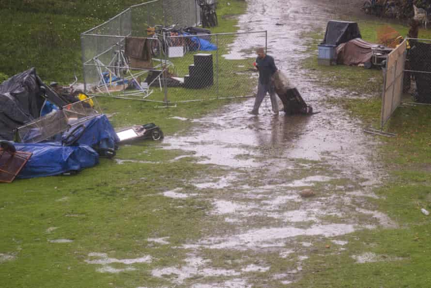 A man drags his belongings through the mud in the encampment.