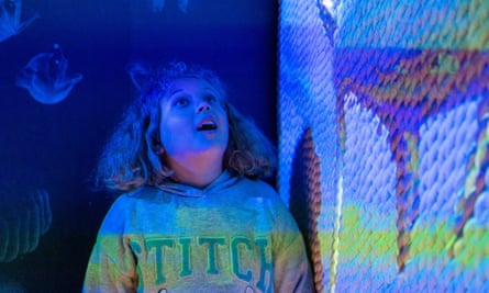 young girl looking immersed in the experience under colourful image projection