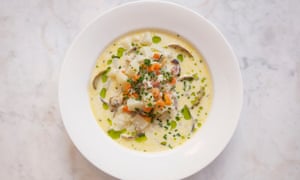 A cream-coloured soup with a pile of clams in the middle