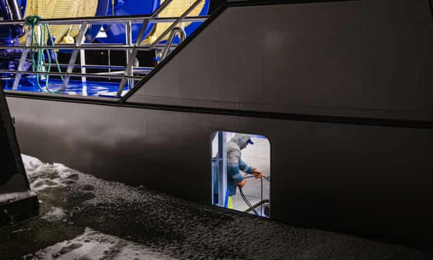 A fisherman working below deck onboard a trawler at night.