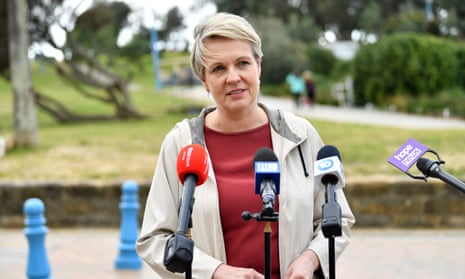 Woman speaks to the media outside wearing a grey jacket and red top