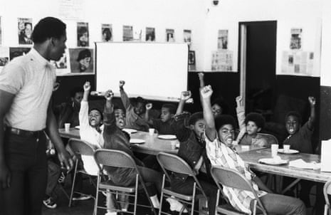 A teacher leads his students with the black power salute and slogans at a Black Panther liberation school.