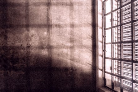 Light comes in through the barred window of a bare room