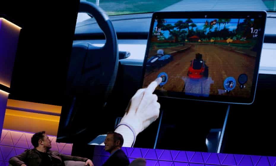 Elon Musk watches a clip of a video game in a Model 3 Tesla in June 2019.