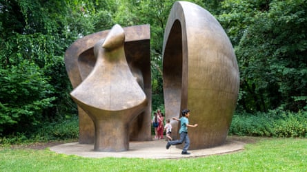 Children play around a large sculpture in a garden setting
