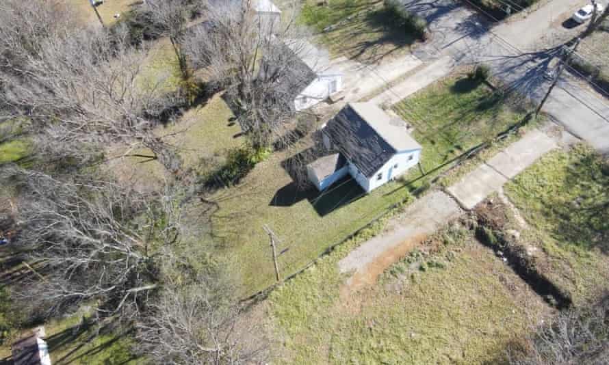 An aerial shot of a tiny house surrounded by grass and trees.