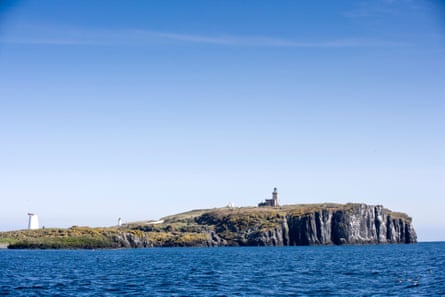 A rocky island with cliffs and three lighthouses or beacons seen on it