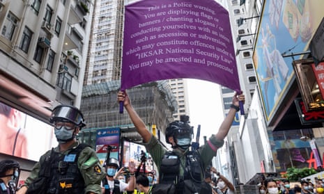 A riot police officer in Hong Kong holds up a purple flag telling protesters they are breaking the law.