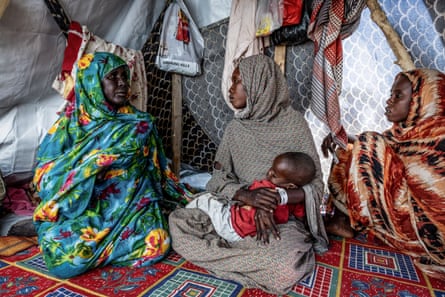 Sudanese refugee Mouda Youssouf Ahmat Fadoul holds her baby while sitting inside a tent at the Tine transit camp, Chad.