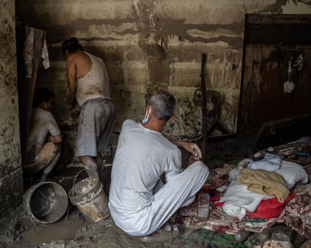 People looking though a mud-covered room