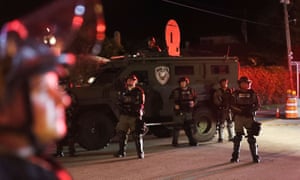 Palm Beach county sheriff officers with in riot gear keep protesters against Donald Trump away from the entrance to the president’s Mar-a-Lago resor.