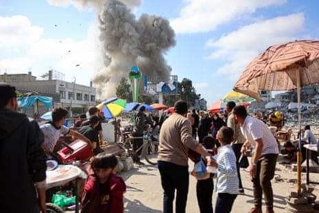 Palestinians look at smoke billowing during Israeli bombardment on the Firas market area in Gaza City on Thursday.