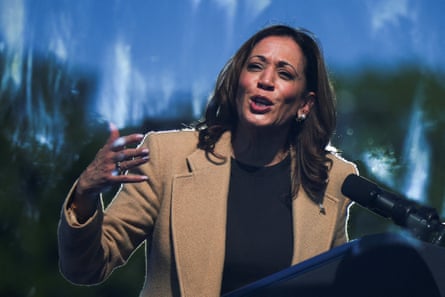 a woman in a tan coat speaks into a microphone