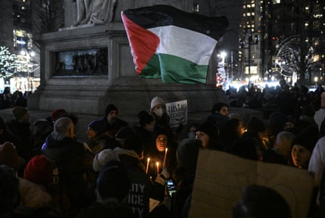 A Palestinian flag is seen at the protest as well as lighted candles and people bundled up against the cold