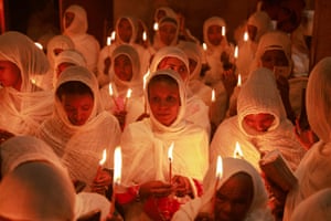 People in white hold candles