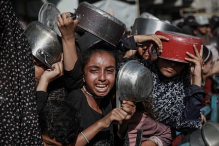 Palestinians form a line to receive hot meals in Gaza’s al-Zeitoun neighbourhood on 31 July