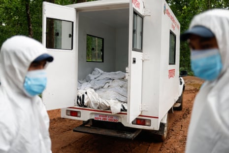 Mask and hazard-suited officers near a van containing dead bodies