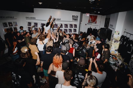 Concert-goers cluster around a band playing in a packed record store