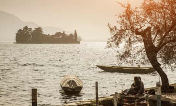 Couple sitting on the edge of Lake Iseo, Italy.casal sentado à beira do Lago Iseo. Fotografia: Imagens Getty