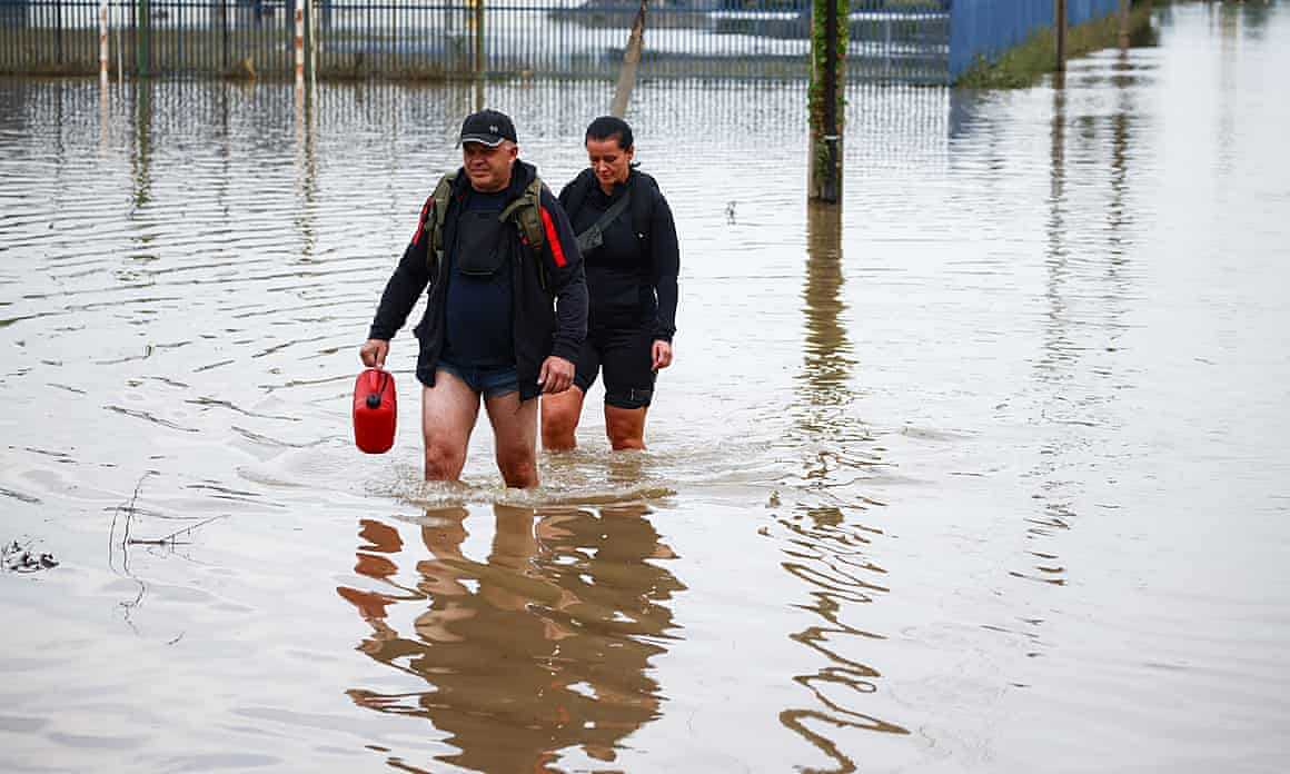 Two people wade through knee-high flood water