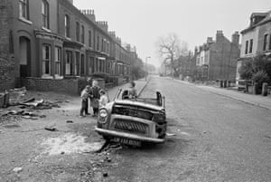 Manchester, 1970. Children play on a ruined car in the street
