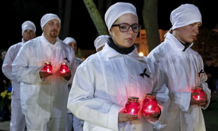 Staff of the Chernobyl nuclear plant hold candles as they visit a memorial, dedicated to firefighters and workers who died after the Chernobyl nuclear disaster.