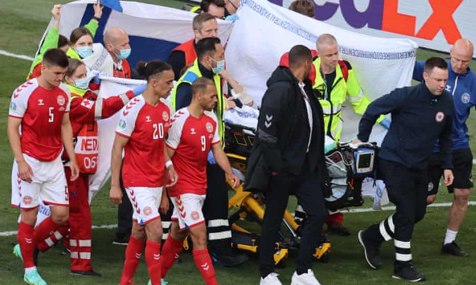 Christian Eriksen’s teammates shield him from view as he is taken off the pitch by medical staff.