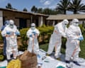 Health workers in full-body protective clothing handle pieces of equipment in the grounds of the hospital