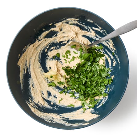 6 Add the garlic and herbs. Puree the garlic (with a garlic crusher, pestle and mortar or heavy knife) and add to the tahini mix. Strip the mint leaves from the stems (or trim the coarser stalks from flat-leaf parsley), then roughly chop until you have about three tablespoons’ worth. Stir two-thirds of the herbs into the tahini mixture, and save the rest as garnish.