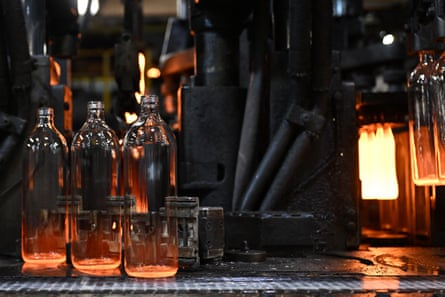 fresh bottles glow in orange, flame-like light as they come off the production line.
