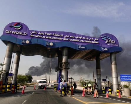 Smoke billows in the background beyond the port's main gate