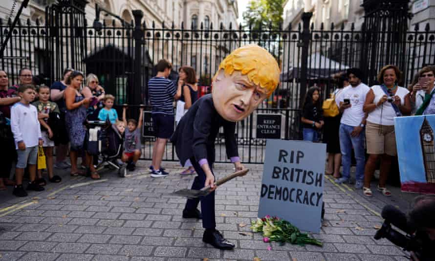 A protester depicting Boris Johnson burying democracy demonstrates outside the gates of Downing Street