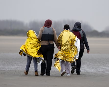 Two children in foil blankets and two women walk along the beach in Gravelines, France, after failing to board a dinghy attempting to sail into the Channel in April.