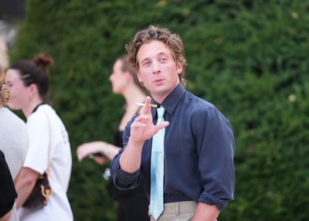 Jeremy Allen White in blue shirt and tie holding a cigarette