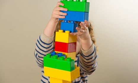preschool child assembling a tower from large plastic bricks