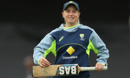 Australia captain Alyssa Healy holds a cricket bat and smiles wearing training kit.