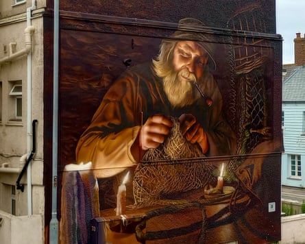 A mural of fisher mending nets by candlelight on the end wall of a building