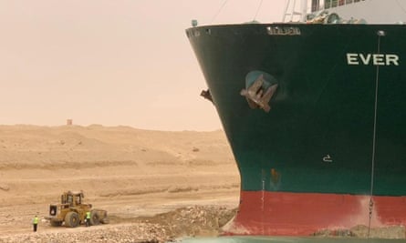 Workers are seen next to the container ship which was hit by strong wind and ran aground in Suez Canal