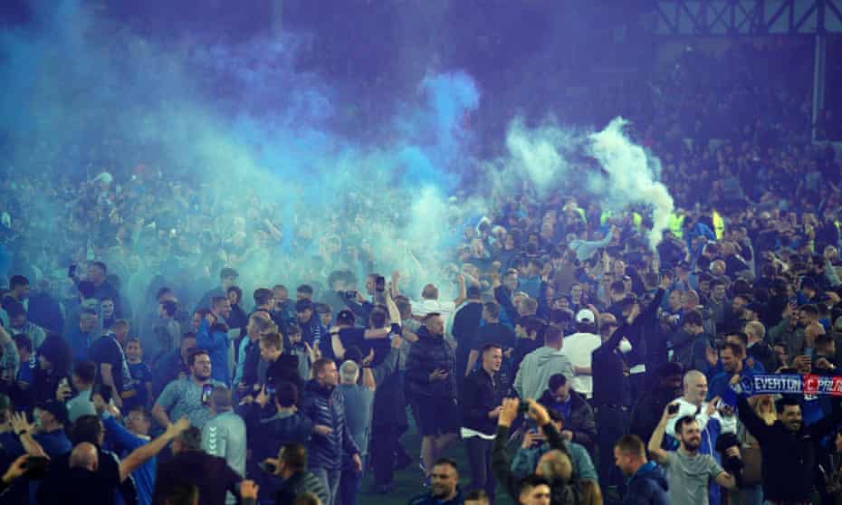 Everton fans celebrate the club’s Premier League survival on the pitch on 19 May.