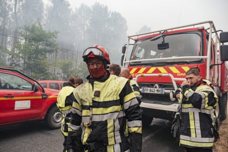 Firefighters in protective gear next to a fire truck