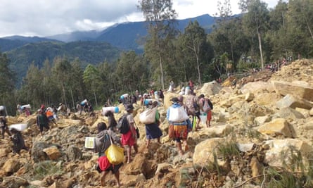 People carry bags after a landslide hit Yambali village in PNG’s Enga province