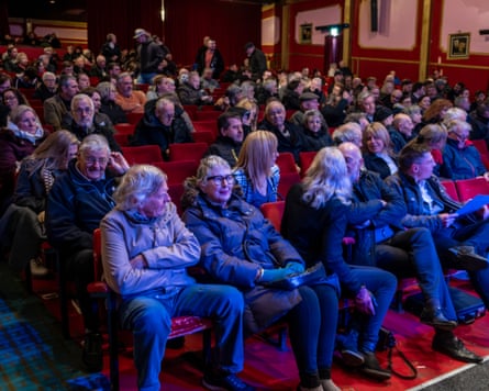 Audience members sitting in rows of red seats