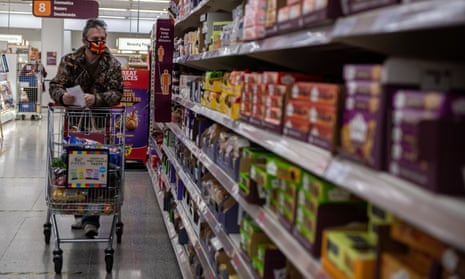 A man wearing a Union Jack flag design face mask shops in a Sainsbury’s supermarket