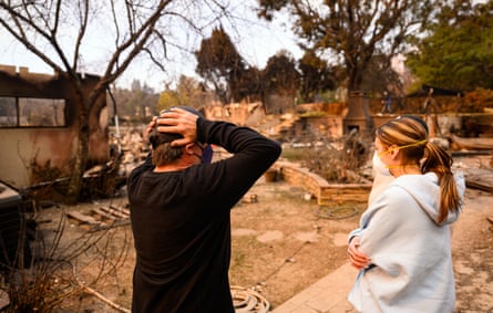 a men and women looking at the destruction of their home from a fire