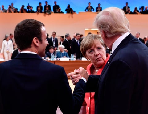 US president Donald Trump and French president Emmanuel Macron shake hands, watched by German chancellor Angela Merkel, at a G20 meeting in Hamburg in 2017