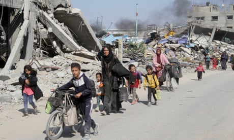 Palestinian women and children fleeing amid rubble of destroyed buildings