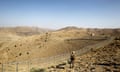 A soldier stands guard along a wire fence that marks the border with Afghanistan in north Waziristan. The terriane is dry and mountainous